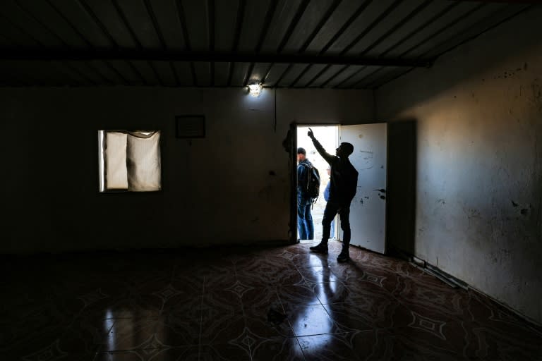 Un proche d'Amina, une fillette de sept ans blessée lors de l'attaque iranienne contre Israël, montre un trou provoqué par un projectile dans le toit d'une maison, le 14 avril 2024 dans le désert du Néguev, dans le sud d'Israël (AHMAD GHARABLI)