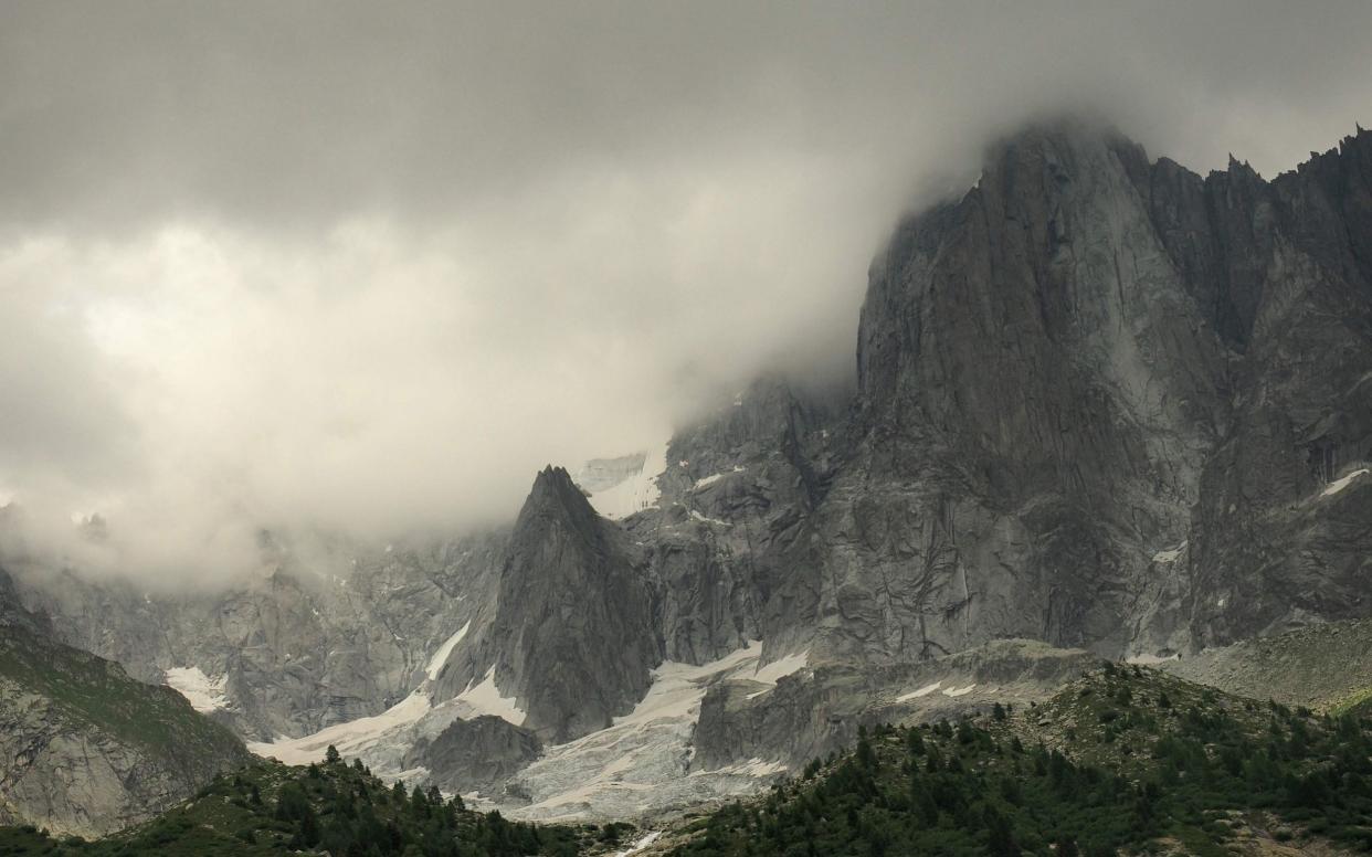 A picture taken on August 10, 2018 shows a detail of Petite Aiguille Verte, hidden by clouds, part of the group of peaks Aiguilles de Chamonix in the Mont Blanc massif, French Alps, in the area where three Italian mountaineers have been reported missing for three days. - AFP