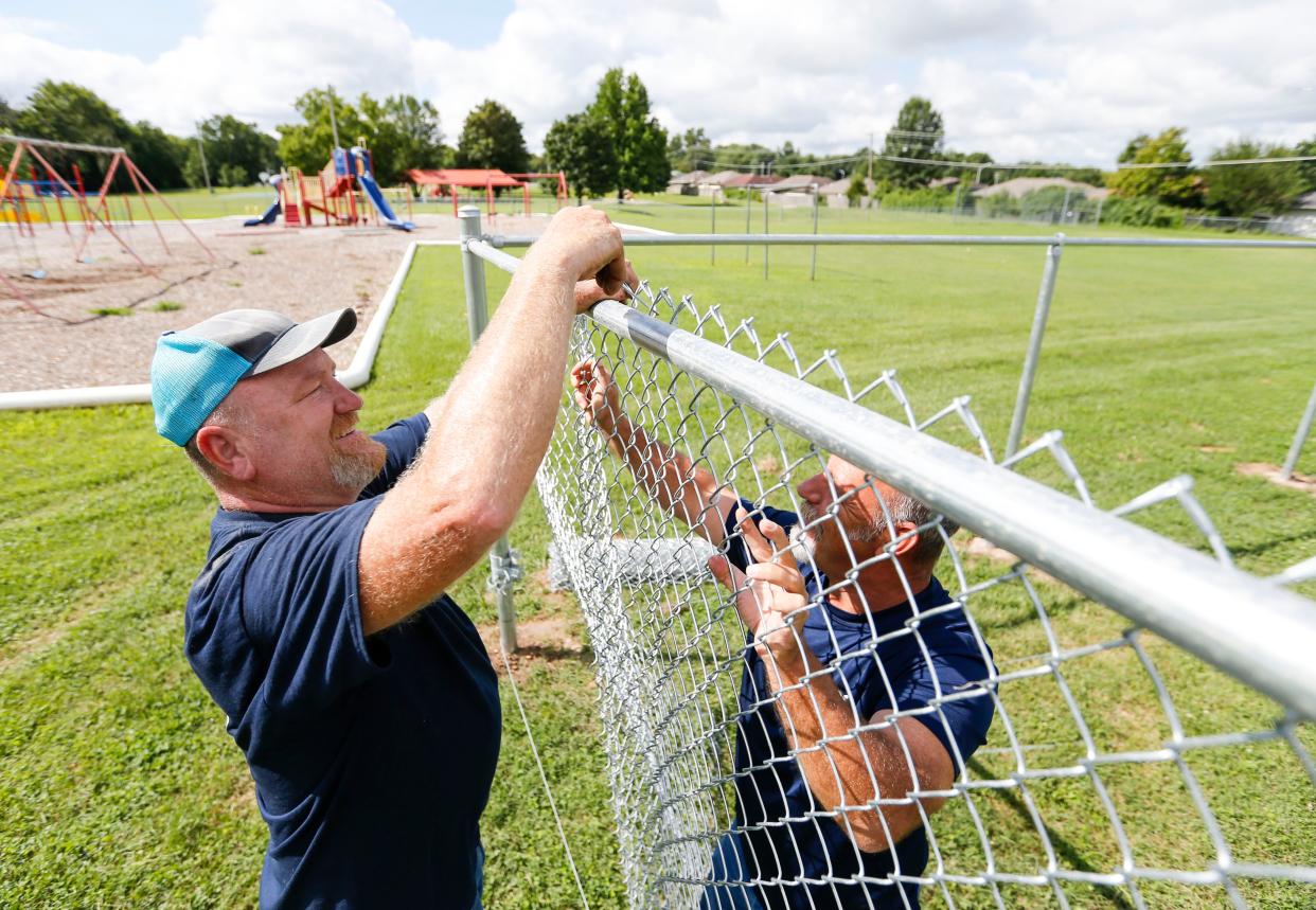 Anchor Fence employees Jason Overholser (left) and John Ott install a fence in the playground area at Bissett Elementary School on Tuesday, Aug. 15, 2023 as part of security upgrades funded by the 2023 bond issue.
