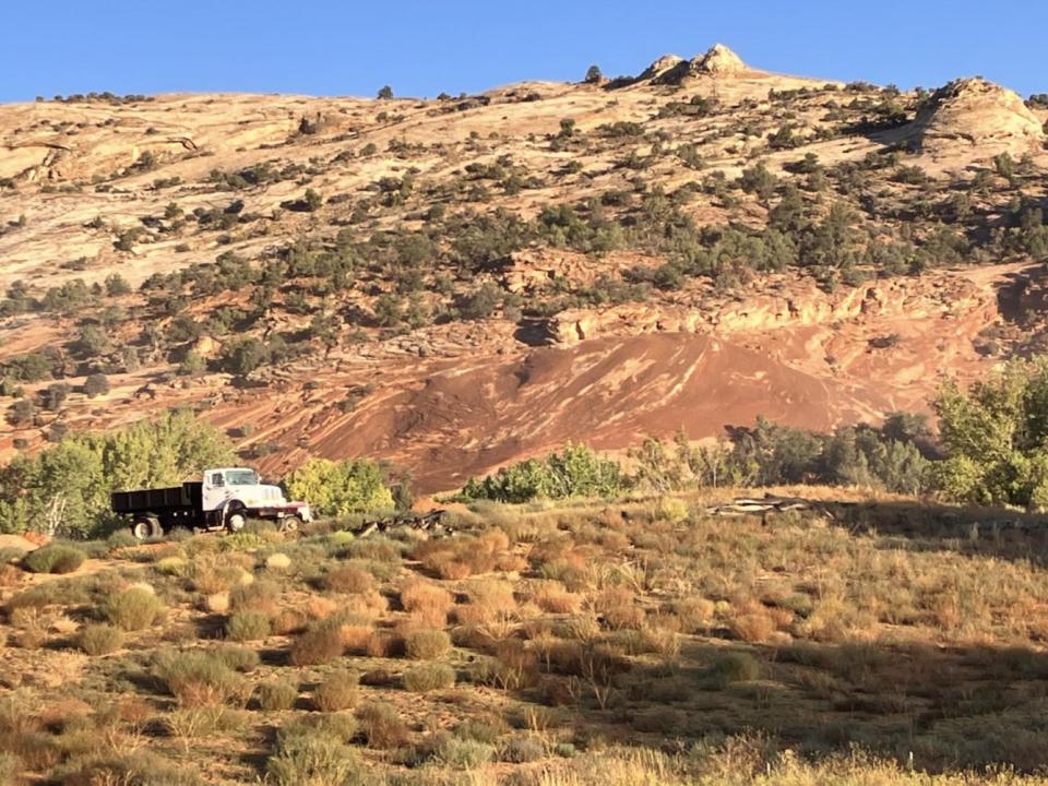 Rolling desert hills with a white truck passing through