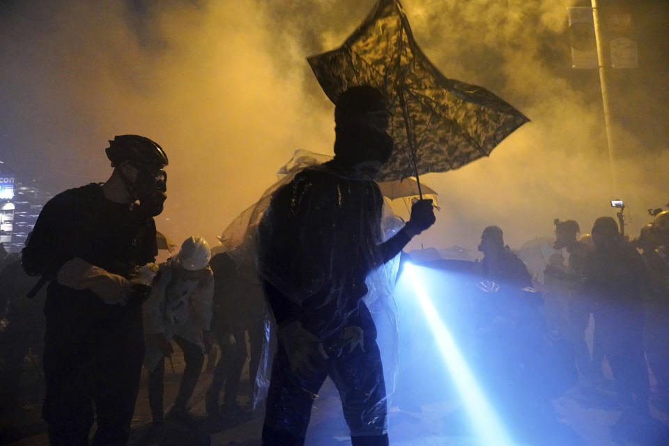 Protestors stand amid smoke on a bridge over a highway leading to the Cross Harbour Tunnel in Hong Kong, Nov. 17, 2019. (Photo: Vincent Yu/AP)