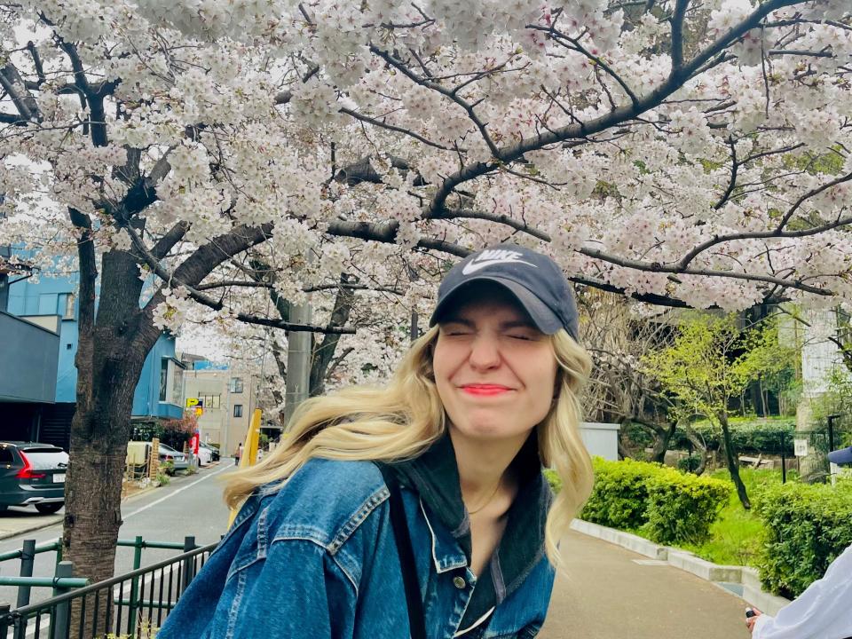 abi posing for a photo in front of a blooming cherry blossom tree in japan