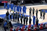Dallas Mavericks players and staff stand during the playing of the national anthem before the first half of an NBA basketball game against the Atlanta Hawks in Dallas, Wednesday, Feb. 10, 2021. (AP Photo/Tony Gutierrez)