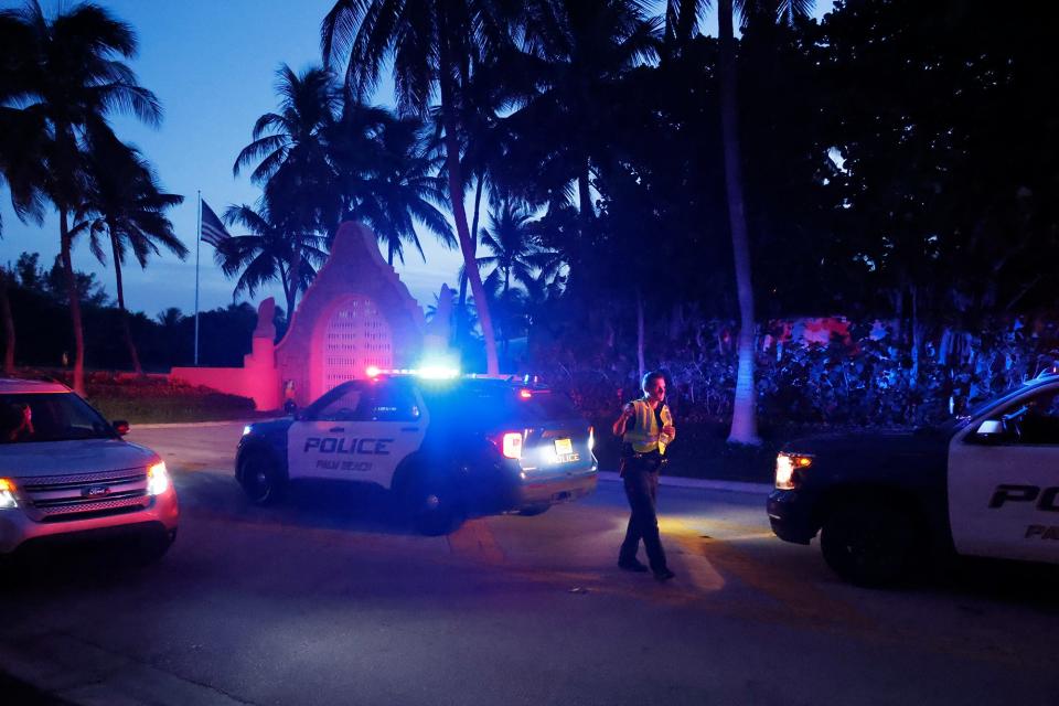 A police officer, police car, and police lights outside of Mar-a-Lago