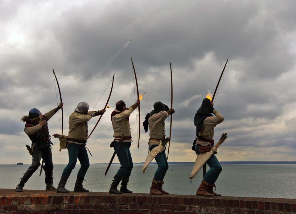 Archers of the Purbrook Bowmen, dressed in Tudor looking clothes, fire a volley of flaming arrows from Southsea Castle into The Solent, towards where the Mary Rose sank in 1545, at Portsmouth on the south coast of England, Thursday May 30, 2013. Henry VIII's flagship sank during a battle against the French navy and was raised from the seabed in 1982. The ceremony was one of the events to mark the opening of the new Mary Rose Museum at Portsmouth Historic Dockyard. In the background, left, is one of the Solent Forts, and at right is part of the Isle Of Wight. (AP Photo / Chris Ison, PA) UNITED KINGDOM OUT, NO SALES, NO ARCHIVE