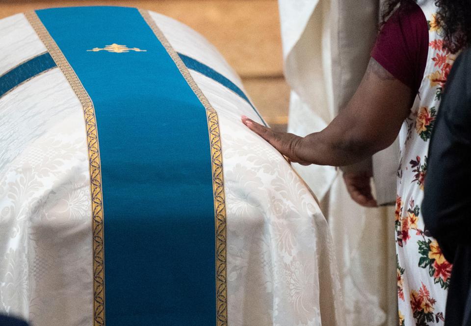 A parishioner touches the casket of the Rev. Joseph Patrick Breen during his funeral Mass at Christ the King Catholic Church Friday, May 27, 2022, in Nashville, Tenn.