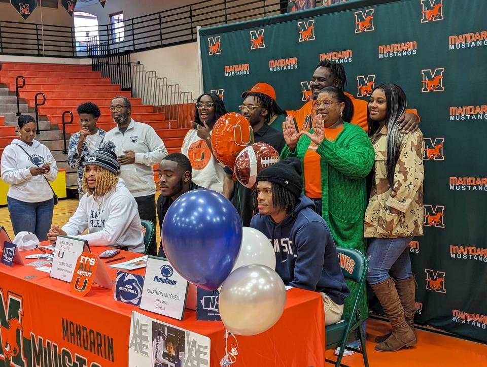 Surrounded by family and friends, Mandarin cornerback A.J. Belgrave-Shorter (Penn State), offensive tackle Deryc Plazz (Miami) and cornerback Jon Mitchell (Penn State) react after signing national letters of intent Wednesday.