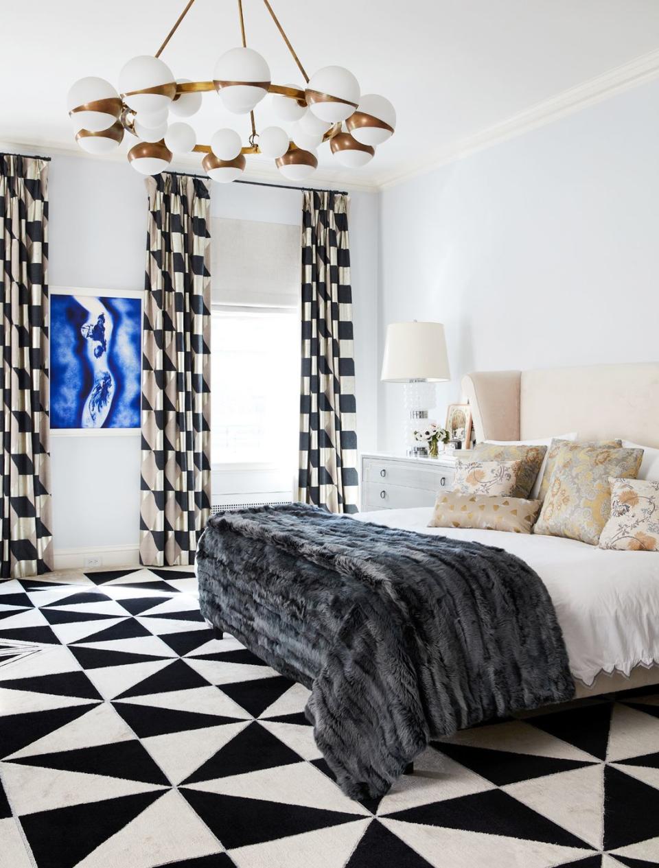 <p>Bold, over-the-top black and white carpeting and drapes blend nicely with the glam light fixture, eye-catching artwork, and luxe throw blanket while the delicate pinks and creams on the bed soften up this bedroom by <a href="https://www.fawngalli.com/" rel="nofollow noopener" target="_blank" data-ylk="slk:Fawn Galli;elm:context_link;itc:0;sec:content-canvas" class="link ">Fawn Galli</a>. </p>