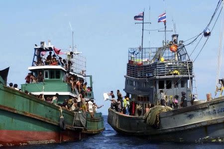 Thai fishermen (R) give some supplies to migrants on a boat drifting 17 km (10 miles) off the coast of the southern island of Koh Lipe, Thailand May 14, 2015. REUTERS/Stringer