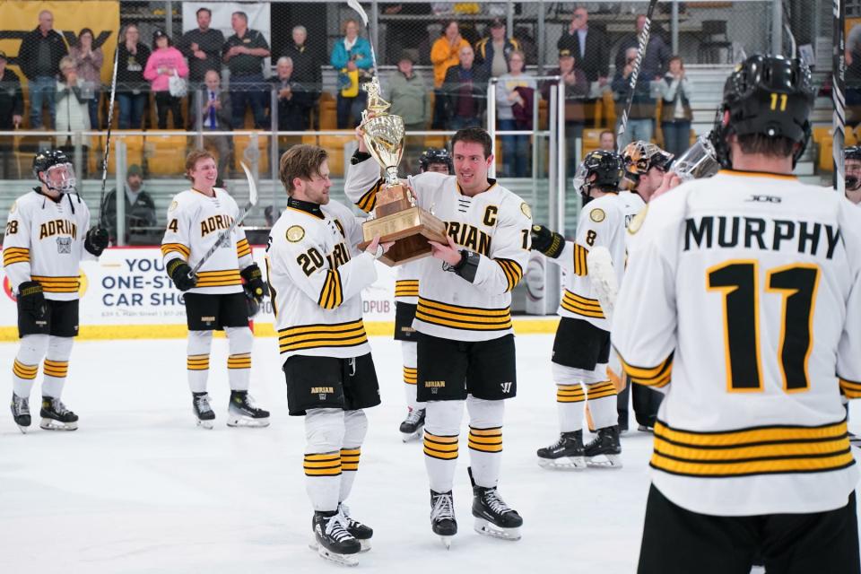 Adrian College captain John Kaljian and assistant Jaden Shields skate with the Peters Cup.