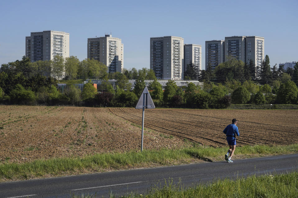 In this Wednesday, April 15, 2020 photo, a man jogs near buildings in the Minguettes district of Venissieux, a suburb of Lyon, central France. They can’t expect much sympathy, but lockdowns and travel restrictions mean small-time drug dealers can’t do business as usual during the coronavirus pandemic. Street sellers in Brussels and Paris have changed their work hours and delivery methods due to the end of public nightlife and a drop in demand. (AP Photo/Laurent Cipriani)