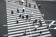 People walk across a crossing near Tokyo Station in Tokyo Thursday, July 29, 2021, a day after the record-high coronavirus cases were found in the Olympics host city. (AP Photo/Kantaro Komiya)