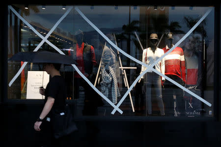 A man walks past a boutique with windows taped as Typhoon Haima approaches in Hong Kong, China, October 21, 2016. REUTERS/Bobby Yip