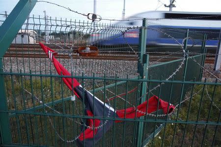 A TGV high speed train passes behind razor-wire fencing close to the Channel Tunnel site on which a sweat shirt is stretched over the barbs to protect asylum seekers who climb over the fence in Calais, northern France, July 29, 2015. REUTERS/Pascal Rossignol