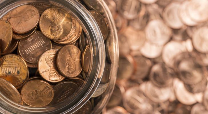 Pennies in a jar on top of a background of pennies. Pennies. Cheap stocks.