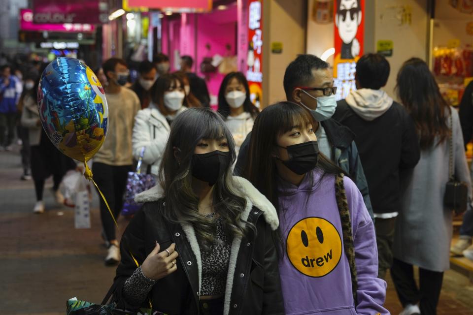People wearing face masks to protect against the spread of the coronavirus, walk on a street in Hong Kong, Friday, Jan. 14, 2022. Hong Kong International Airport said Friday that it would ban passengers from over 150 countries and territories from transiting in the city for a month, as it sought to stem the transmission of the highly contagious omicron variant of the coronavirus. (AP Photo/Kin Cheung)