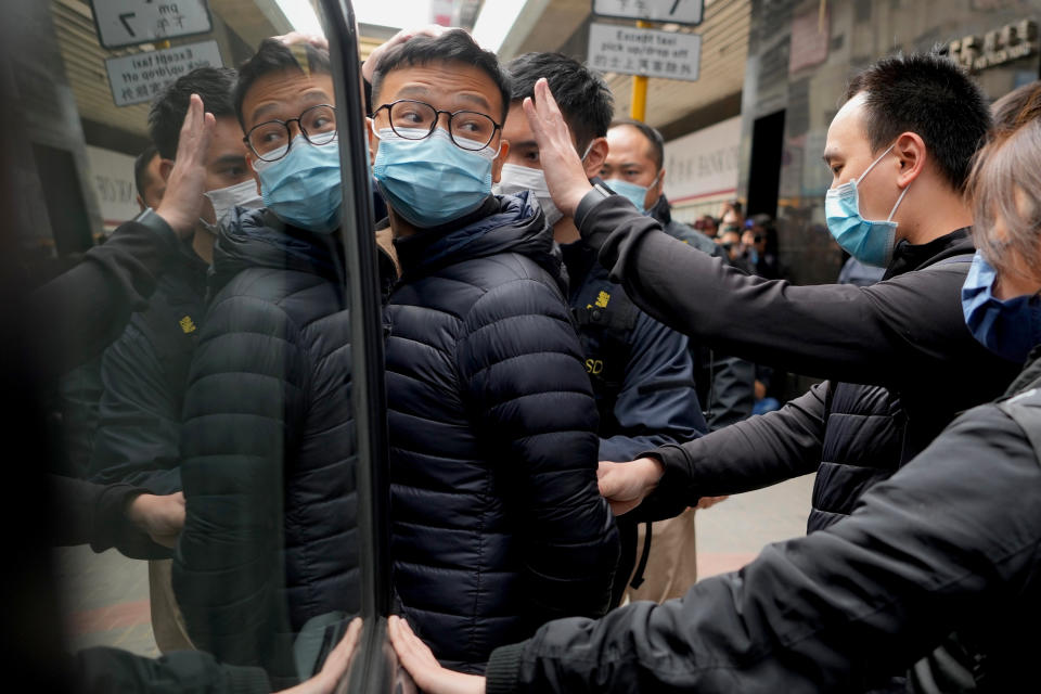 Editor of Stand News Patrick Lam, center, is escorted by police officers into a van after they searched evidence at his office in Hong Kong, Wednesday, Dec. 29, 2021. Hong Kong police raided the office of the online news outlet on Wednesday after arresting several people for conspiracy to publish a seditious publication. (AP Photo/Vincent Yu)