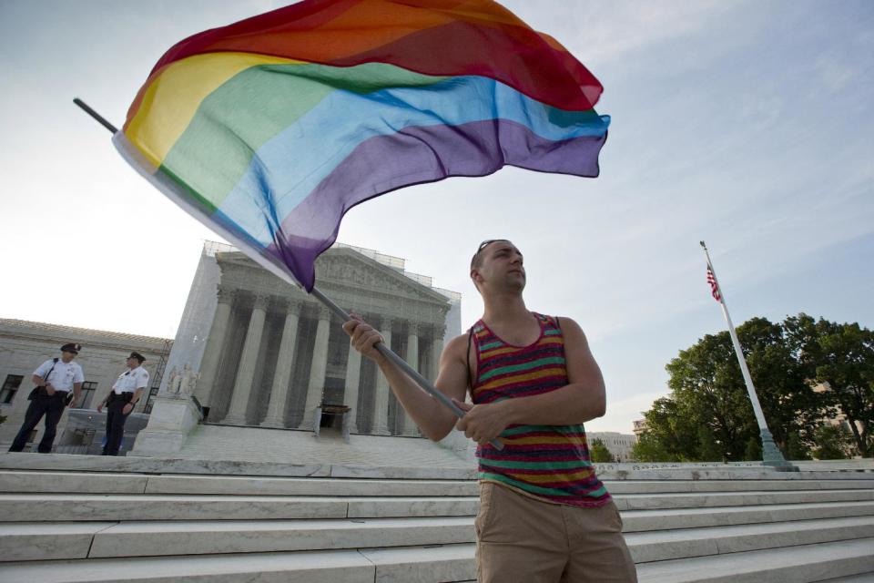 FILE- In this June 26, 2013 file photo, gay rights advocate Vin Testa waves a rainbow flag in front of the Supreme Court in Washington. Both sides in the gay marriage debate agree on one thing: It’s time for the Supreme Court to settle the matter. Even a justice said recently that she thinks so, too. That emerging consensus makes it likely that the justices soon will agree to take up the question of whether the Constitution forbids states from defining marriage as the union of a man and a woman. While a final ruling isn’t likely before June of next year, a decision to get involved could come as soon as the end of this month. (AP Photo/J. Scott Applewhite, File)