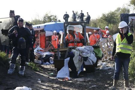 French CRS riot police secure the area as workmen tear down a makeshift shelter on the second day the evacuation of migrants and their transfer to reception centers in France, as part of the dismantlement of the camp called the "Jungle" in Calais, France, October 25, 2016. REUTERS/Neil Hall