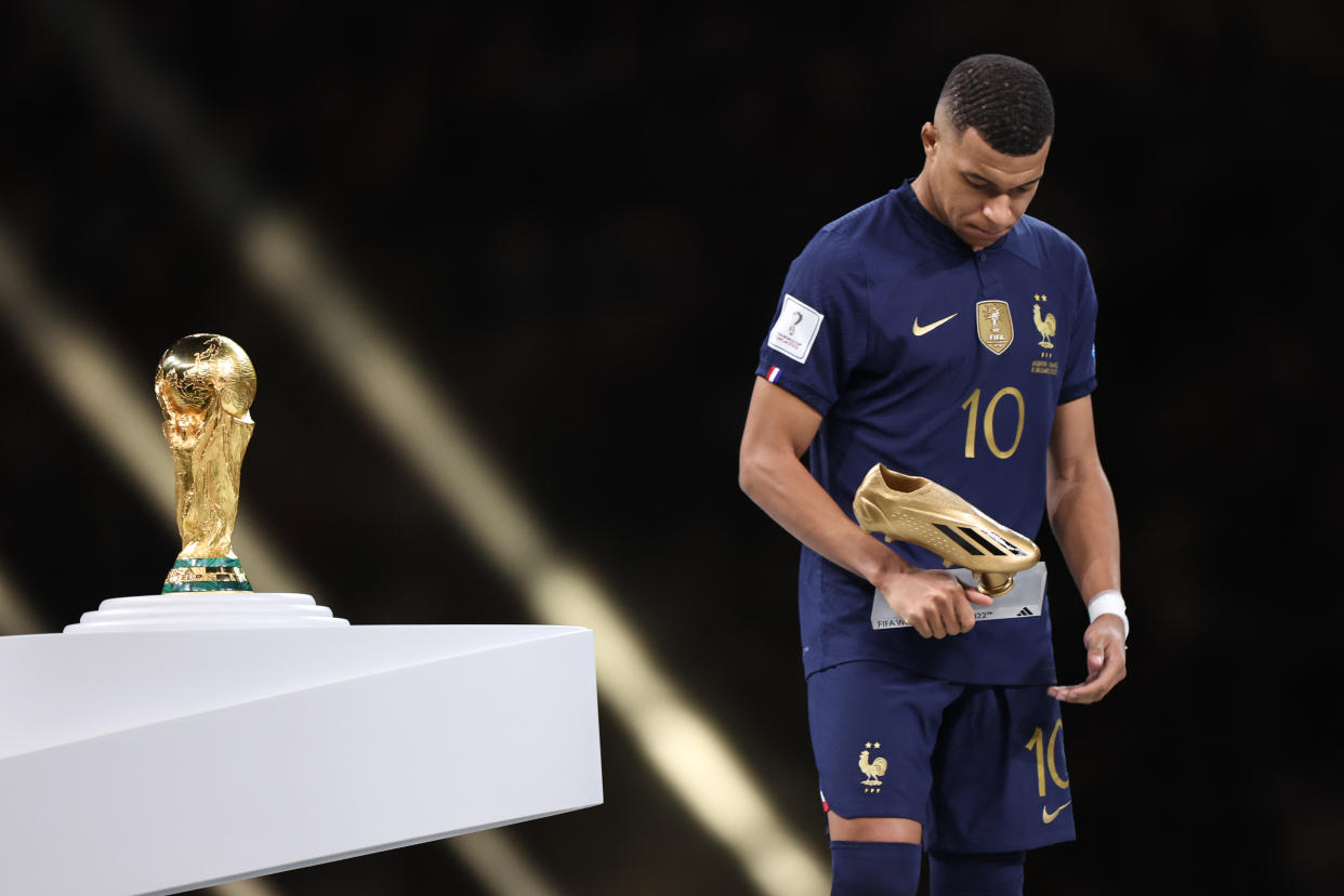 LUSAIL CITY, QATAR - DECEMBER 18: Kylian Mbappe of France walks past the FIFA World Cup Trophy after losing in the final with his golden boot trophy during the FIFA World Cup Qatar 2022 Final match between Argentina and France at Lusail Stadium on December 18, 2022 in Lusail City, Qatar. (Photo by Matthew Ashton - AMA/Getty Images)