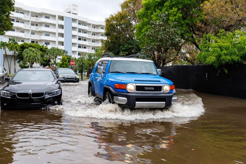 Cars go through the flooded road cause by heavy rains at North Bay Rd and 179th Dr. in Sunny Isles Beach, Fla., Wednesday, April 12, 2023. A torrential storm bought heavy showers, gusty winds and thunderstorms to South Florida on Wednesday and prompted the closure of Fort Lauderdale-Hollywood International Airport and the suspension of high-speed commuter rail service in the region.