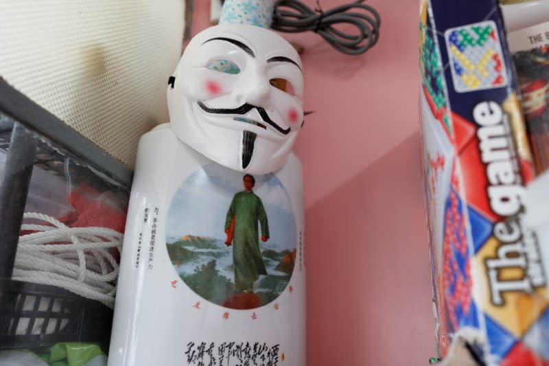 A Guy Fawkes mask is placed on a vase with an image of China's late Chairman Mao Zedong at Derek Tai's apartment in Hong Kong