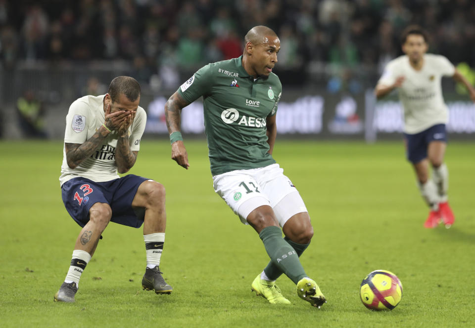 Saint-Etienne's Gabriel Silva, right, challenges for the ball as PSG defender Dani Alves covers his face after he was hurt during the French League One soccer match between Saint-Etienne and Paris Saint-Germain, at the Geoffroy Guichard stadium, in Saint-Etienne, central France, Sunday, Feb. 17, 2019. (AP Photo/Laurent Cipriani)