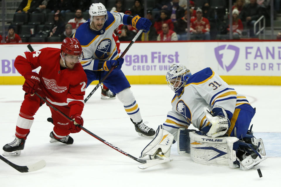 Buffalo Sabres goaltender Dustin Tokarski (31) deflects a shot by Detroit Red Wings center Pius Suter (24) with Sabres defenseman Colin Miller (33) helping defend the goal during the first period of an NHL hockey game Saturday, Nov. 27, 2021, in Detroit. (AP Photo/Duane Burleson)