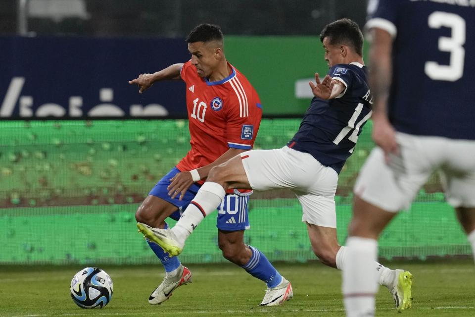 Chile's Alexis Sanchez, left, fights for the ball with Paraguay's Adrian Cubas during a qualifying soccer match for the FIFA World Cup 2026, at Monumental Stadium in Santiago, Chile, Thursday, Nov. 16, 2023. (AP Photo/Esteban Felix)