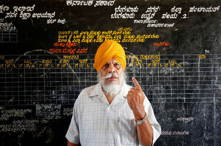 FILE PHOTO: A man displays his finger marked with indelible ink as he poses for a photo outside a polling station during Karnataka assembly elections in Bengaluru, India, May 12, 2018. REUTERS/Abhishek N. Chinnappa/File Photo