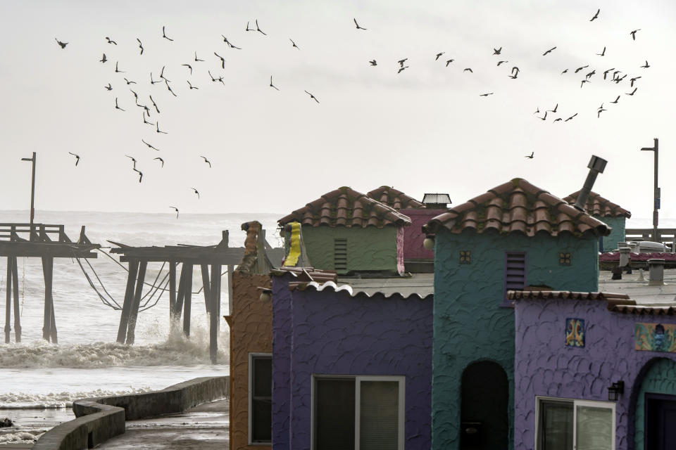 Birds fly over the Capitola Wharf, damaged from storm waves, in Capitola, Calif., Thursday, Jan. 5, 2023. Damaging hurricane-force winds, surging surf and heavy rains from a powerful “atmospheric river” pounded California on Thursday, knocking out power to tens of thousands, causing flooding, and contributing to the deaths of at least two people, including a child whose home was hit by a falling tree.(AP Photo/Nic Coury)