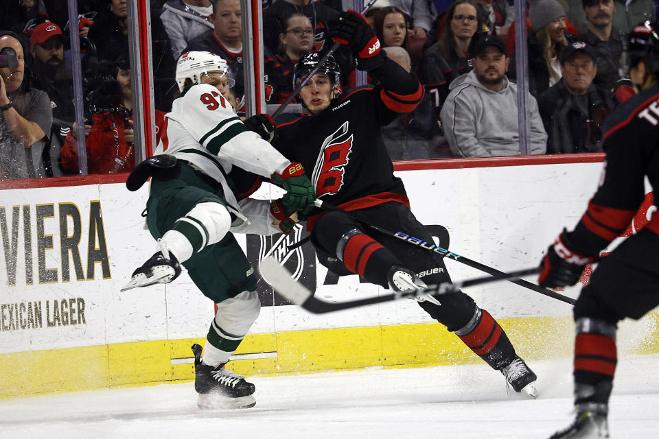 Minnesota Wild's Kirill Kaprizov (97) and Carolina Hurricanes' Brady Skjei (76) collide during the first period of an NHL hockey game in Raleigh, N.C., Sunday, Jan. 21, 2024. (AP Photo/Karl B DeBlaker)