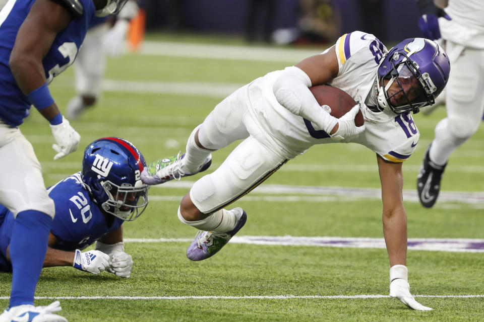 Minnesota Vikings wide receiver Justin Jefferson (18) is tackled by New York Giants safety Julian Love (20) after catching a pass during the second half of an NFL football game, Saturday, Dec. 24, 2022, in Minneapolis. The Vikings won 27-24. (AP Photo/Bruce Kluckhohn)