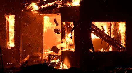 A house burns as firefighters battle a fast-moving wildfire that destroyed homes driven by strong wind and high temperatures forcing thousands of residents to evacuate in Goleta, California, U.S., early July 7, 2018. REUTERS/Gene Blevins