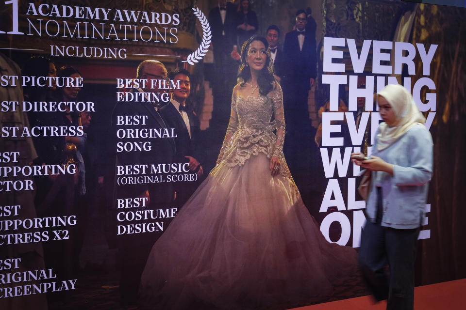 People walk next to giant posters of Michelle Yeoh during the 95th Academy Awards Live View event at a cinema in Kuala Lumpur, Malaysia, Monday, March 13, 2023. Michelle Yeoh was nominated for the Academy Award for best actress. (AP Photo/Vincent Thian)