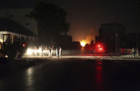 Libya Shield Force members are seen near a building on fire, which witnesses say was hit by a rocket, after clashes between rival militias in the Sarraj district of Tripoli August 23, 2014. REUTERS/Stringer