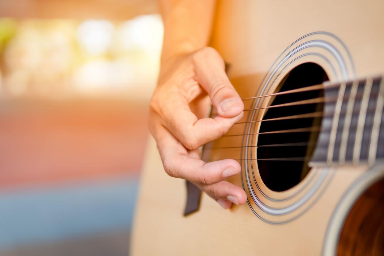 Musician playing guitar classic and singing song, close up hand