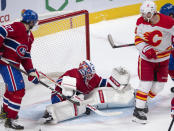 Montreal Canadiens goaltender Jake Allen (34) makes a save as Calgary Flames' Matthew Tkachuk, right, and Montreal Canadiens Alexander Romanov, left, look on during the second period of an NHL hockey game Wednesday, April 14, 2021 in Montreal. (Ryan Remiorz/Canadian Press via AP)