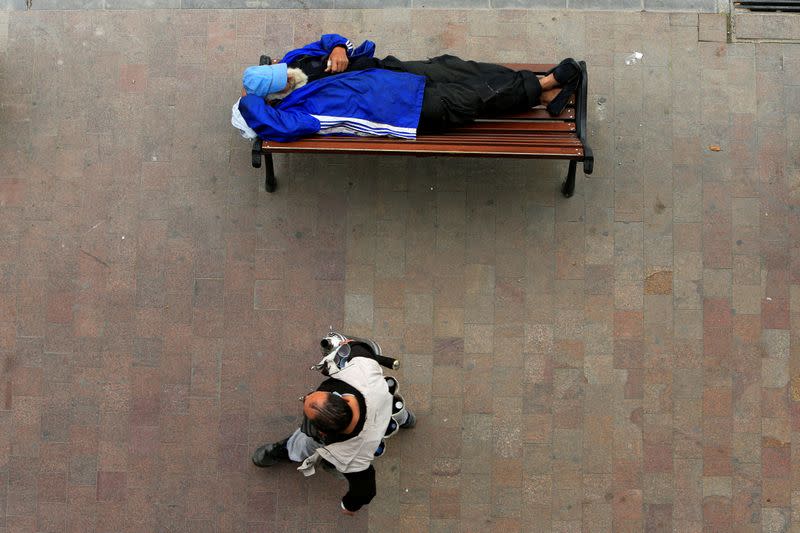 A homeless man sleeps on a bench