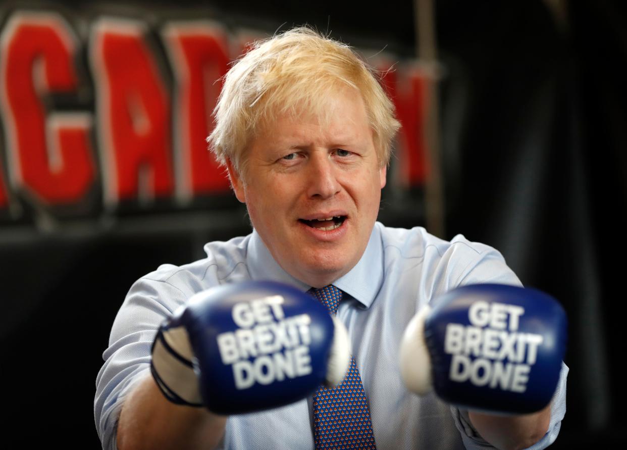 Britain's Prime Minister and leader of the Conservative Party, Boris Johnson wears boxing gloves emblazoned with "Get Brexit Done" as he poses for a photograph at Jimmy Egan's Boxing Academy in Manchester north-west England on November 19, 2019, during a general election campaign trip. - Britain will go to the polls on December 12, 2019 to vote in a pre-Christmas general election. (Photo by Frank Augstein / POOL / AFP) (Photo by FRANK AUGSTEIN/POOL/AFP via Getty Images)