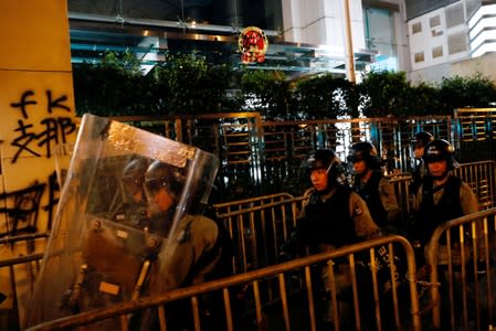 Riot police walk past anti-extradition graffiti outside the Chinese Liaison Office after a march to call for democratic reforms, in Hong Kong