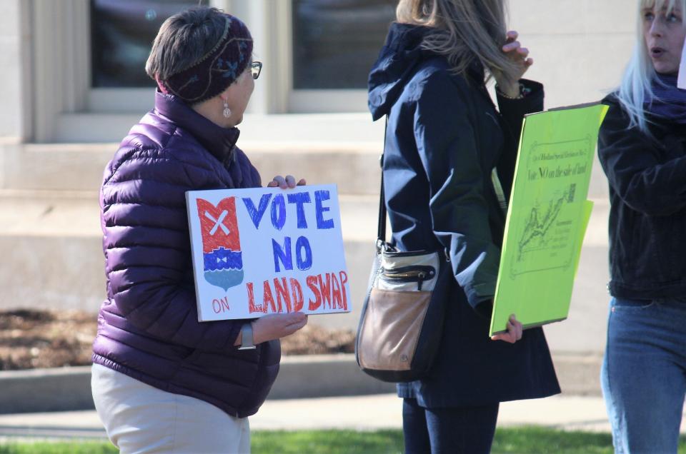 Holland residents hold signs along River Avenue on Wednesday, April 26, advocating against the May 2 land sale ballot proposal.