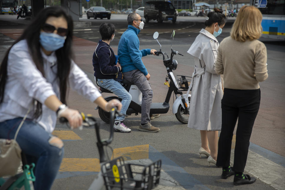 People wear face masks to protect against the spread of the new coronavirus as they wait to cross an intersection in Beijing, Wednesday, April 15, 2020. China reported several dozen new coronavirus cases on Wednesday, mostly from overseas. (AP Photo/Mark Schiefelbein)