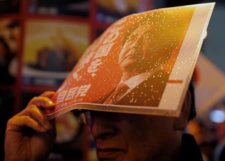 A supporter of the Liberal Democratic Party waits in the rain for the arrival of the party's leader, Japan's Prime Minister Shinzo Abe, at an election campaign rally in Tokyo, Japan October 21, 2017. REUTERS/Kim Kyung-Hoon