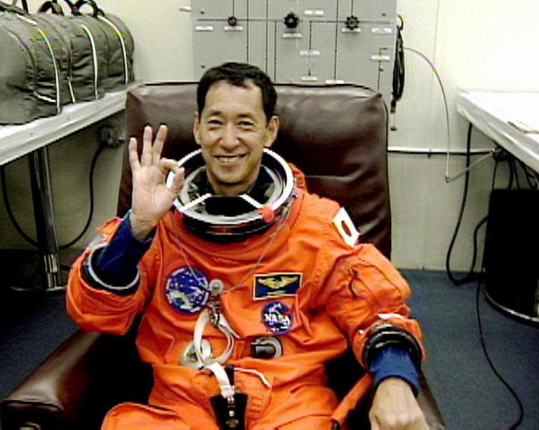 Space Shuttle Endeavour crewmember Japanese Mission Specialist Mamoru Mohri gives an OK sign on February 11, 2000 as he is suited up at Kennedy Space Center's astronaut crew quarters