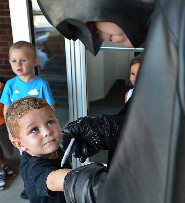 Ryan Duncan gets his arm autographed by Leonard Robinson dressed as Batman during a visit with children at the Morris Memorial Day Care in Kanawha City. Photo: AP