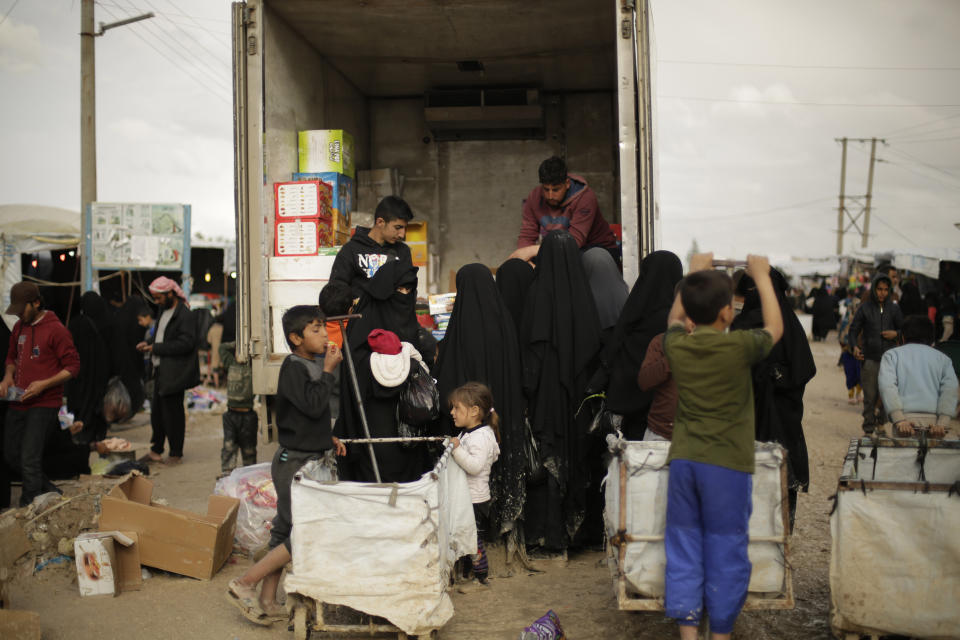 In this March 31, 2019, photo, women purchase goods from the back of a truck in the marketplace at Al-Hol camp, near Hassakeh, Syria. Al-Hol camp is home to 73,000 people who streamed out of the Islamic State group’s last pockets, including the village of Baghouz, the final site to fall to the SDF in March. Nearly the entire population of the camp is women or children, since most men were taken for screening by the SDF to determine if they were fighters. (AP Photo/Maya Alleruzzo)