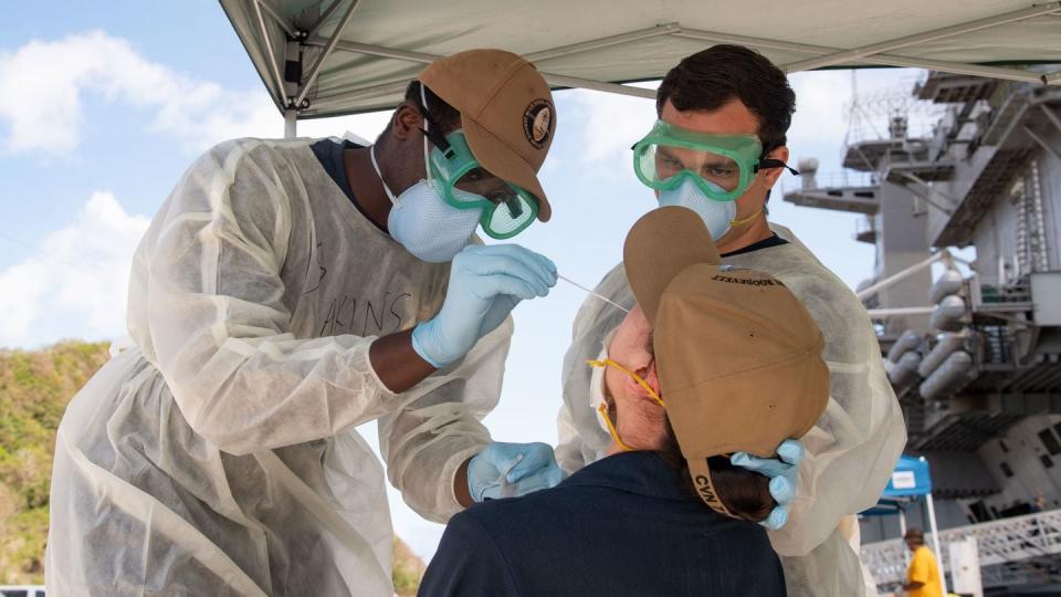 Sailors from the aircraft carrier Theodore Roosevelt are tested for COVID-19 in Guam in April 2020. (Navy)