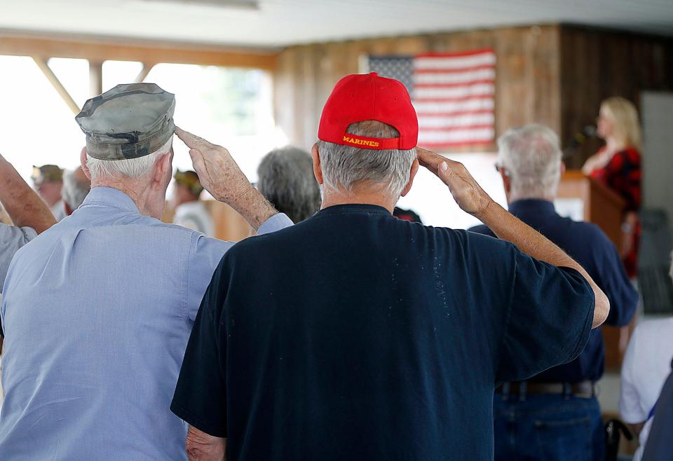 Veterans salute as Melanie Miller sings the national anthem during a service honoring veterans at the Ashland County Fair.