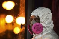 In this photo released by Malaysia's Ministry of Health, a health worker wearing a full protective suit waits for the arrival of evacuated Malaysians from China's Wuhan, the epicenter of the new coronavirus outbreak, at Kuala Lumpur International Airport in Sepang, Malaysia, Wednesday, Feb. 26, 2020. U.S. health officials warned Tuesday that the burgeoning coronavirus is certain to spread more widely in the country at some point, even as their counterparts in Europe and Asia scrambled to contain new outbreaks of the illness. (Muzzafar Kasim/Malaysia's Ministry of Health via AP)